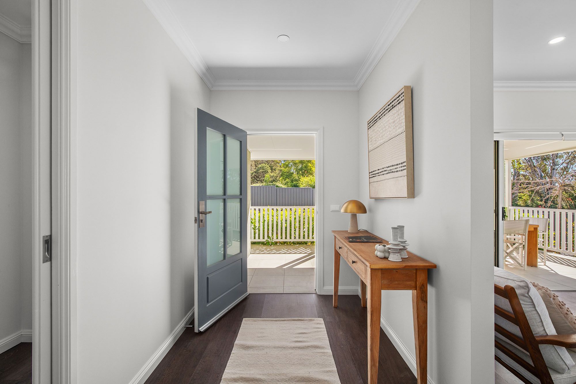 Light-filled entrance hallway with timber flooring, white walls and a glass-panelled front door at Woodside Bundanoon.