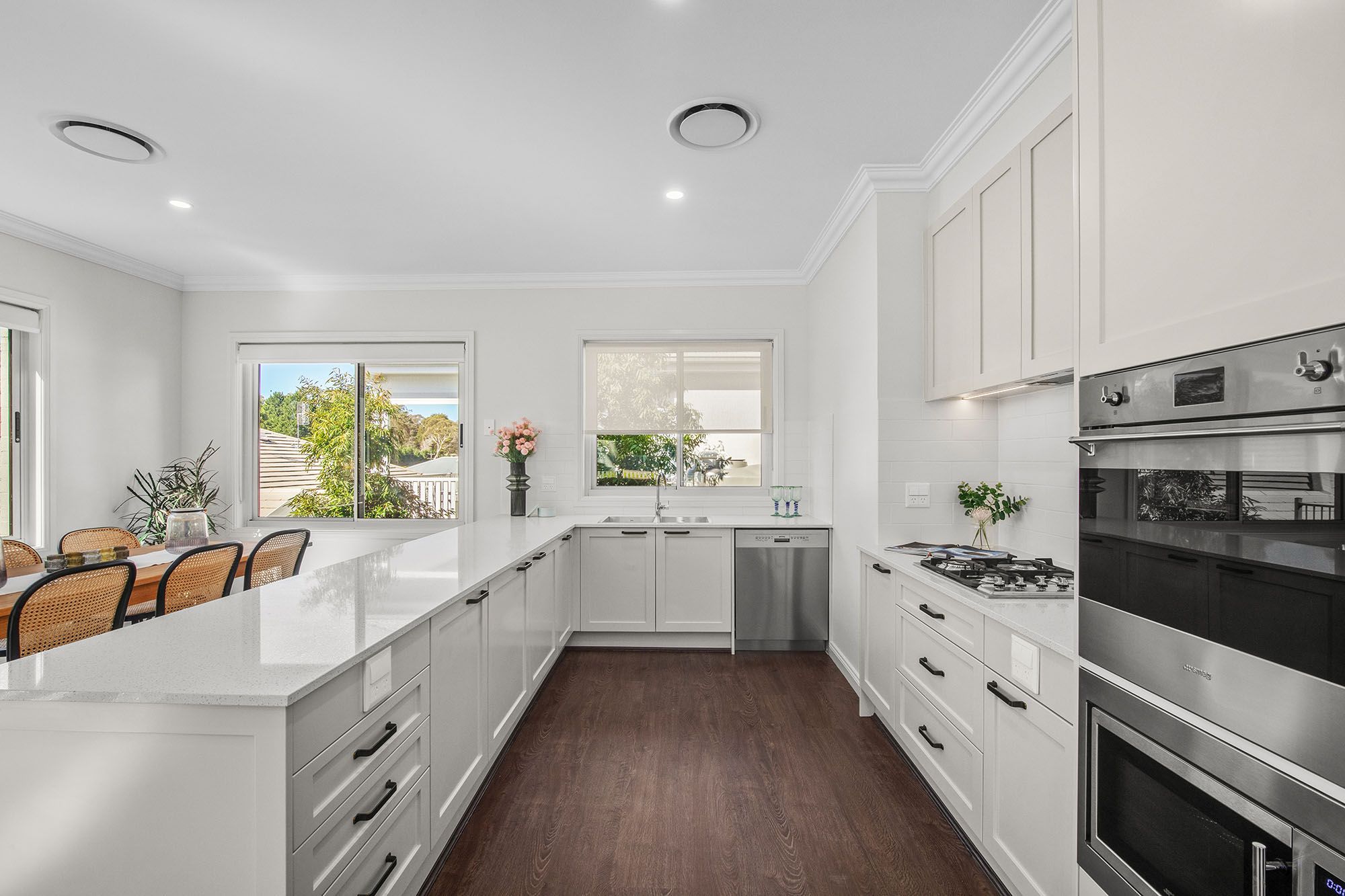 Light-filled kitchen at Woodside Bundanoon, featuring white cabinetry, generous bench space and large windows.
