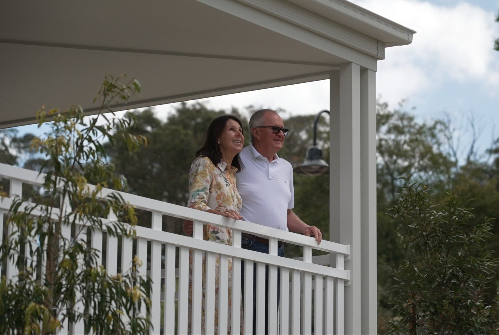 Couple enjoying the view from a covered verandah overlooking the leafy surroundings at Woodside Bundanoon.